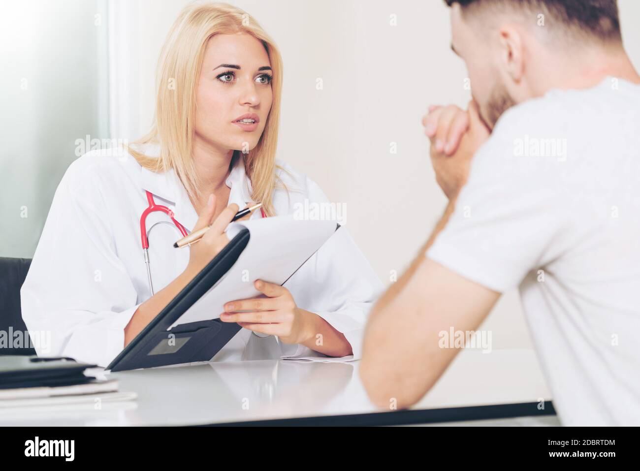 Frau Doktor ist im Gespräch und die Untersuchung der männlichen Patienten im Krankenhaus. Gesundheitswesen und medizinische Betreuung. Stockfoto