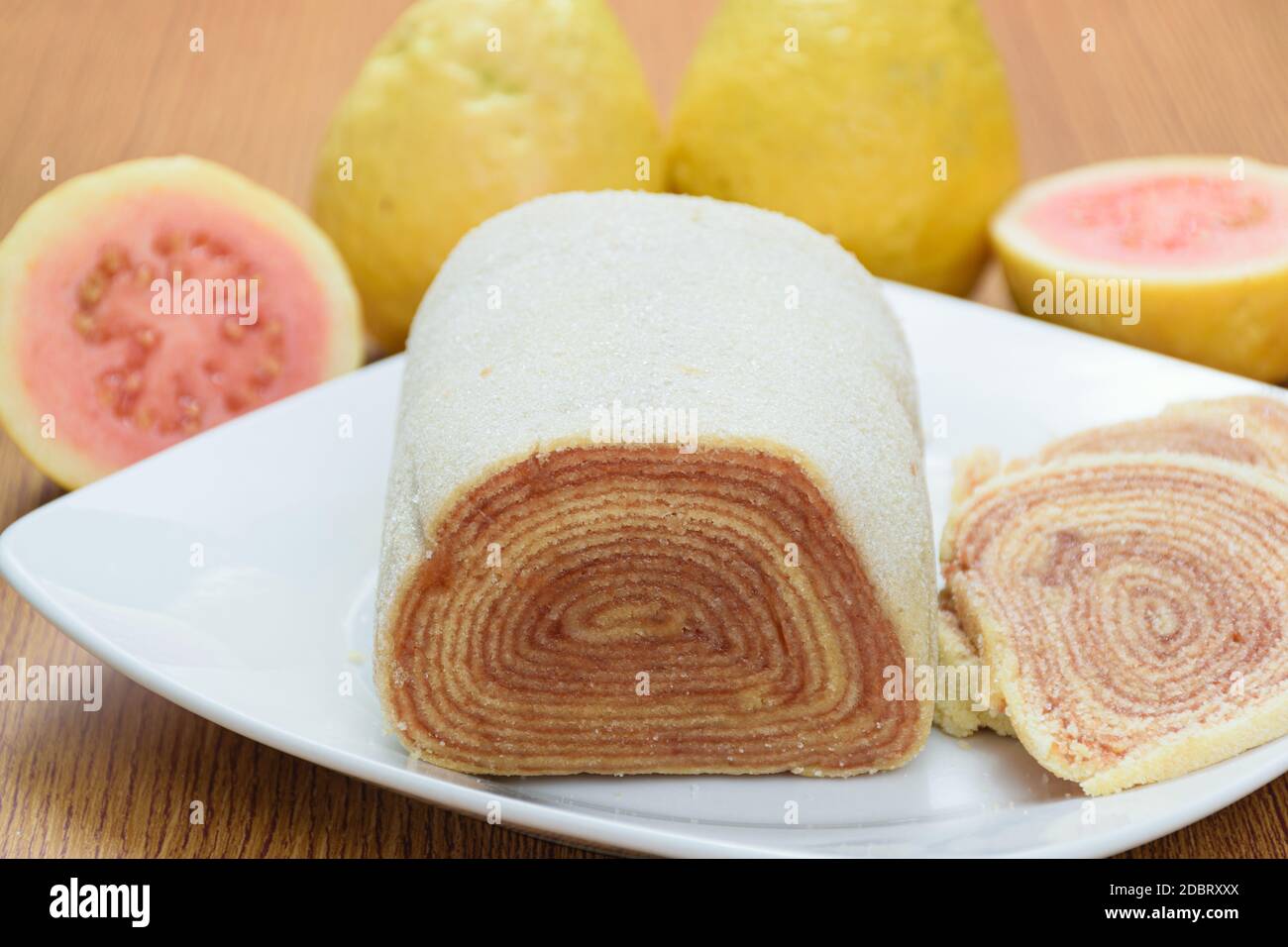 Nahaufnahme von bolo de rolo (Kuchenrolle) neben Guavas. Traditionelle brasilianische Süßigkeit. Stockfoto