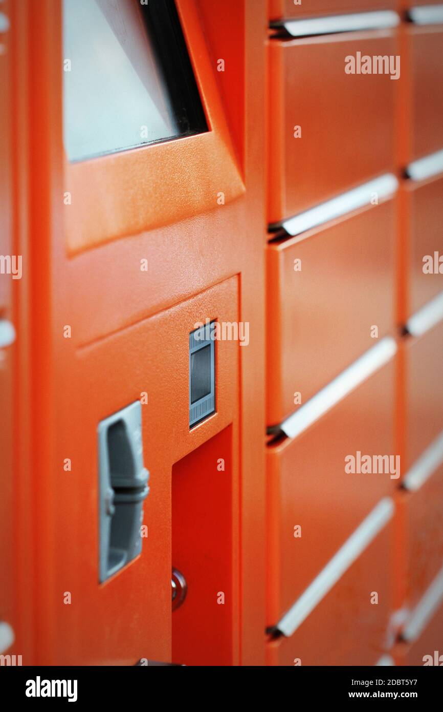 Self-Service-Terminal für Paketpost mit orangefarbener Fassade. Konzept: Lieferung, selbst, einfach, einfach. Stockfoto