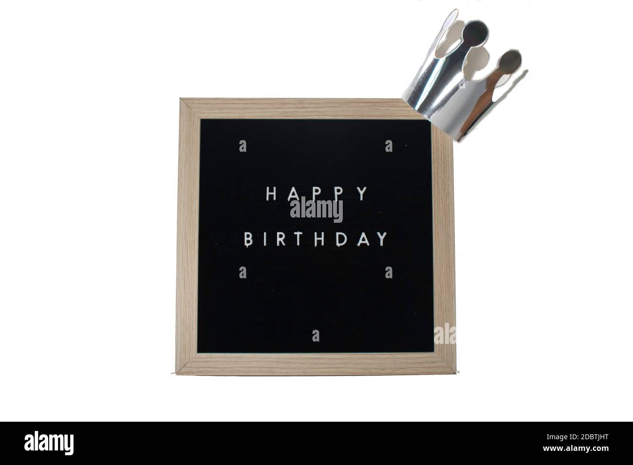 Ein Schild mit Birke-Rahmen, das Happy Birthday in weißen Buchstaben mit einer silbernen Krone auf einem rein weißen Hintergrund sagt Stockfoto