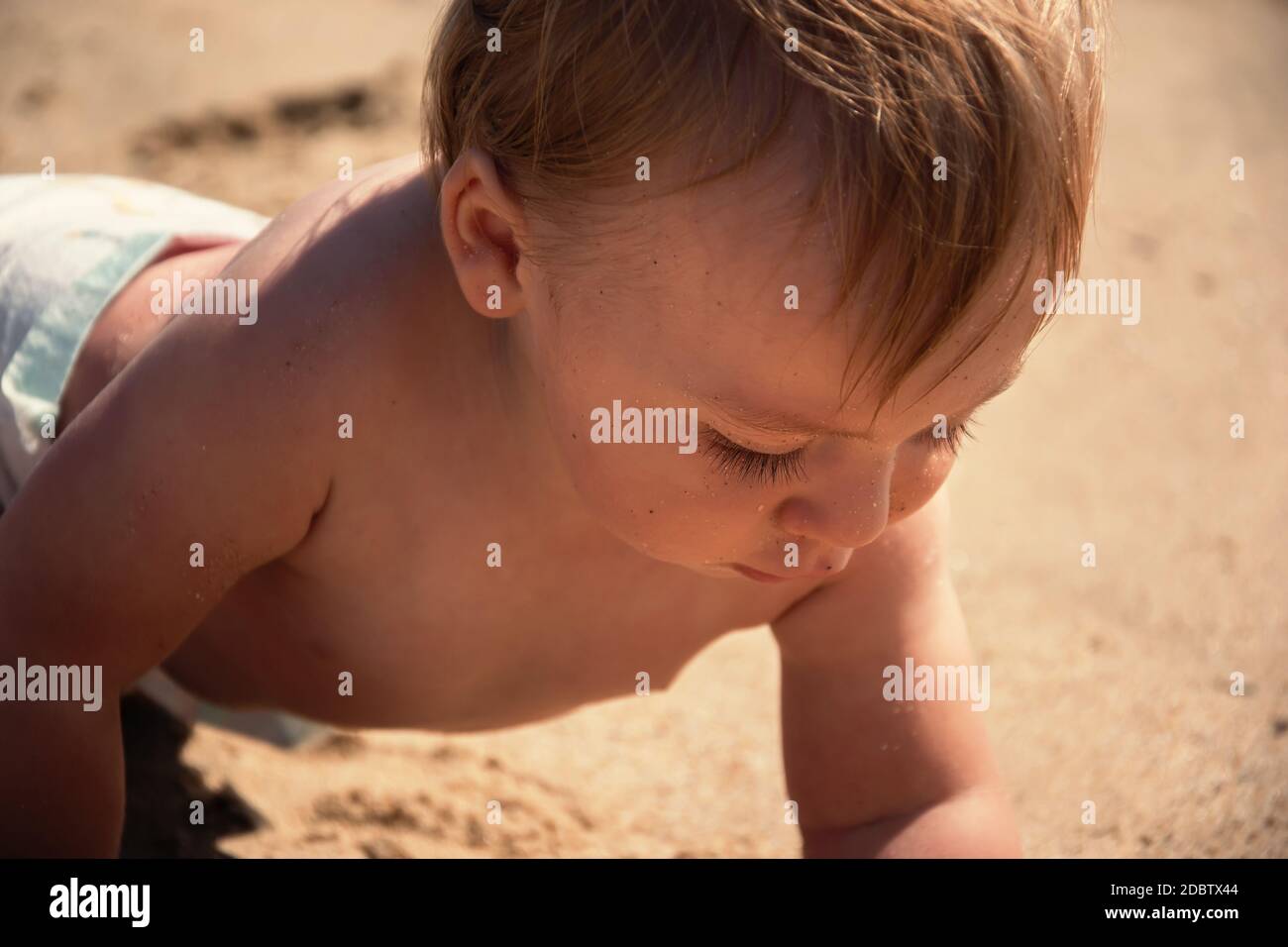 Baby Junge entdecken Sand am tropischen Strand aus nächster Nähe. Neugierig Kleinkind Porträt, die Untersuchung Sandstrand im Sommer. Aktives kaukasisches kleines Kind. Curio Stockfoto