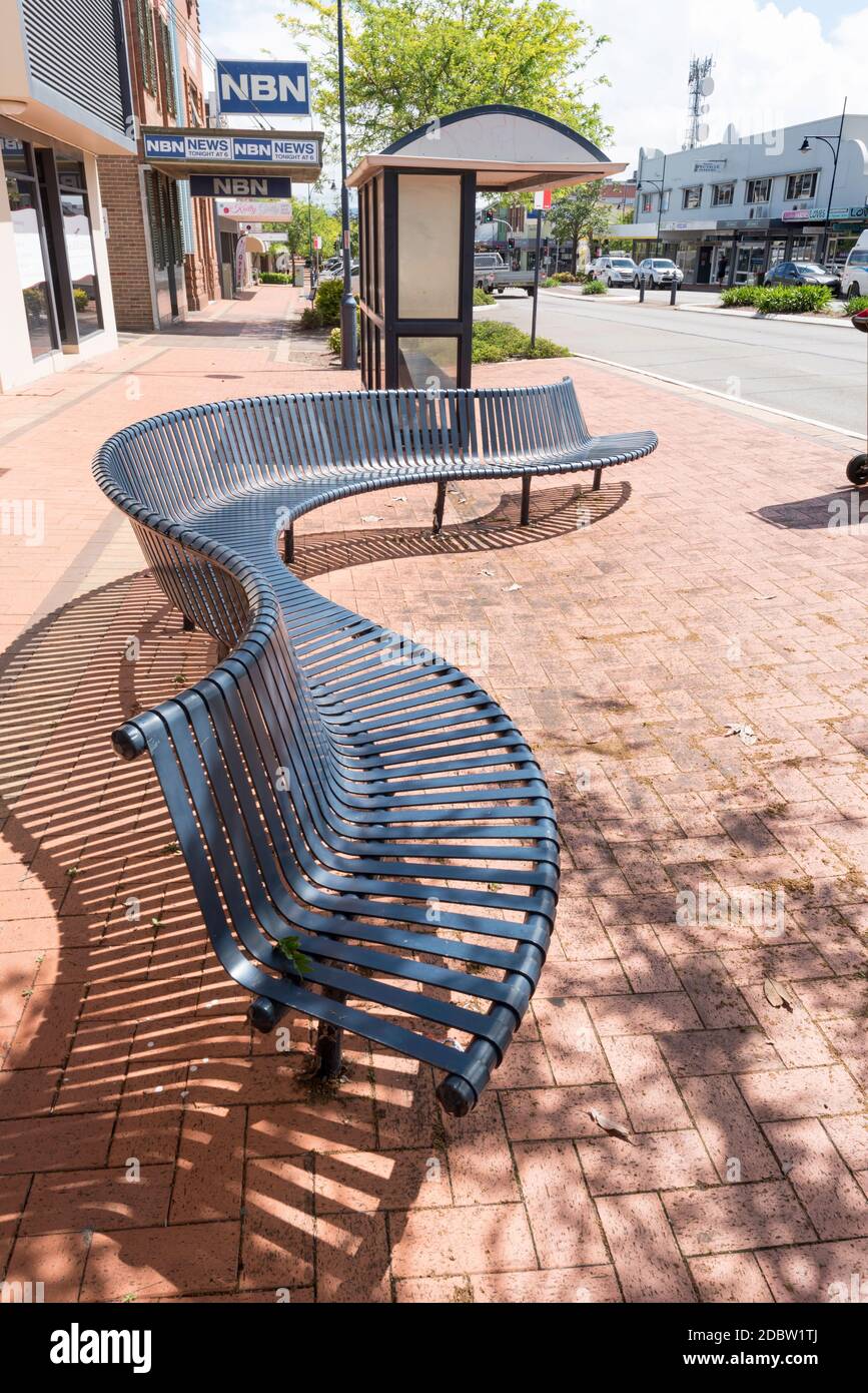 Öffentliche Sitzgelegenheiten im Freien in Schlangenform oder Schlangenform und ein überdachter Sitzplatz Bushaltestelle in der Hauptstraße von Taree auf der Mittlere Nordküste von New South Wales Australien Stockfoto