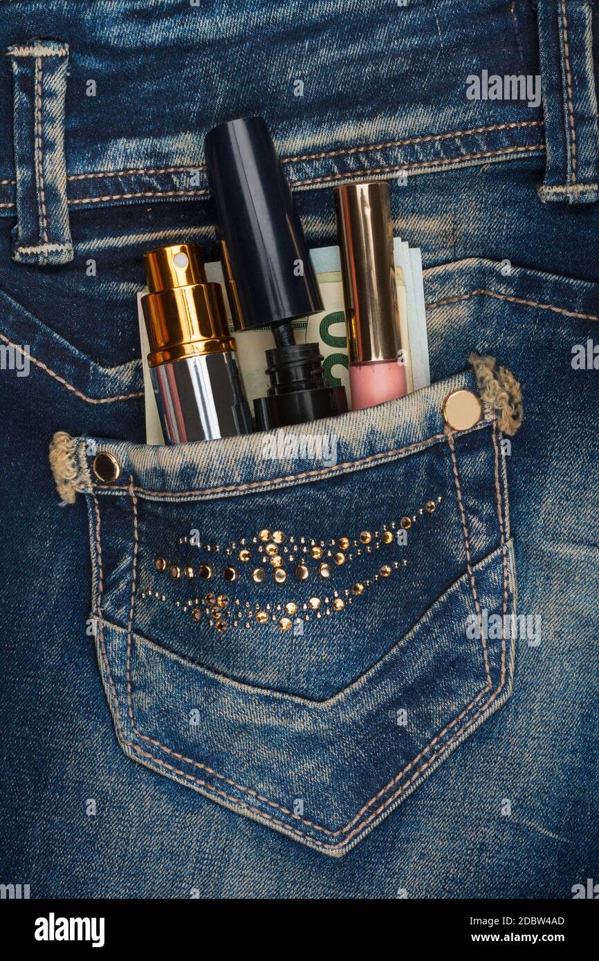 Kosmetik und Geld aus der Tasche seiner Jeans sticks mit Strass, als Hintergrund Stockfoto