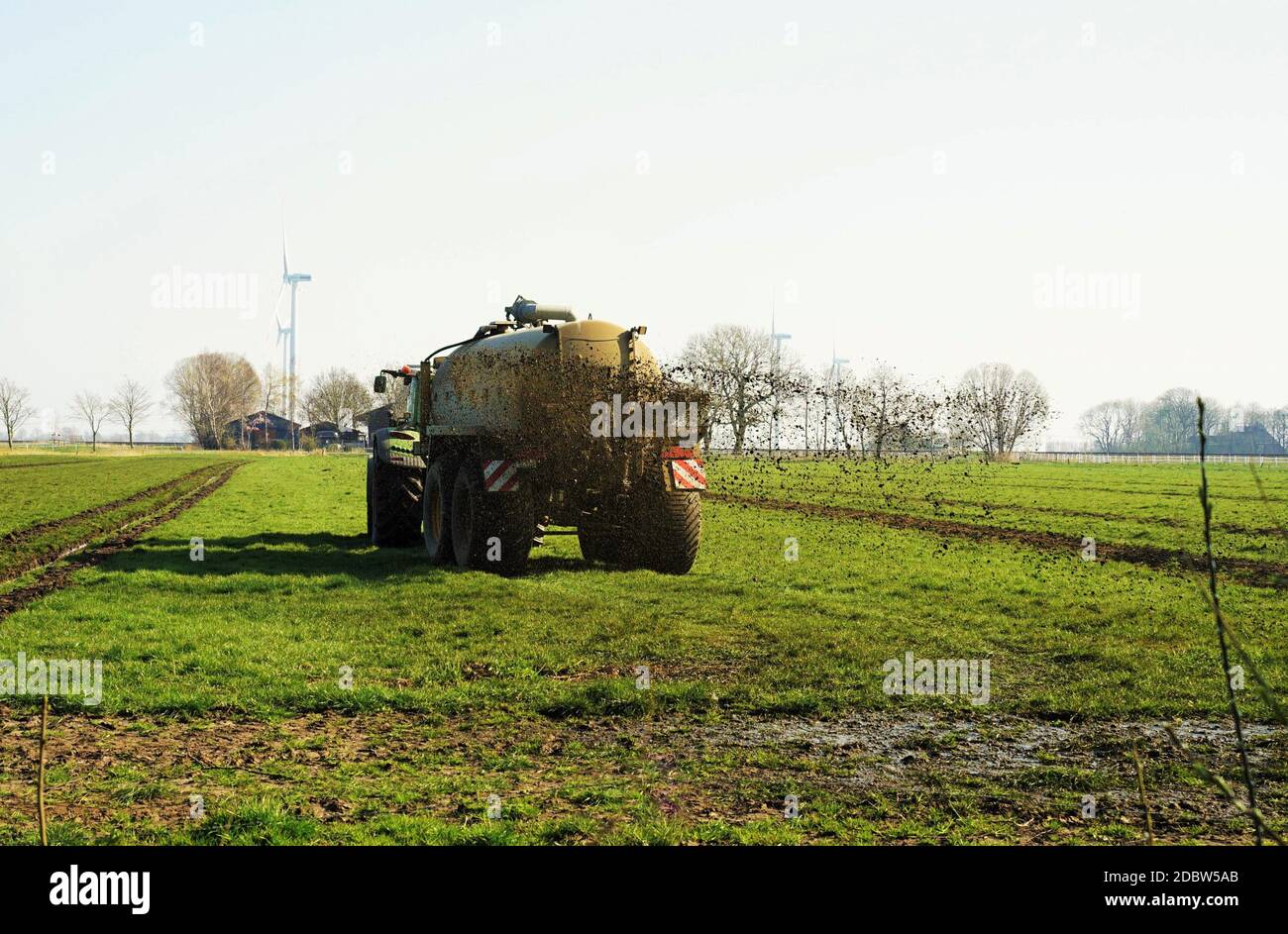 Traktor im März treibt Gülle auf dem Feld an Stockfoto