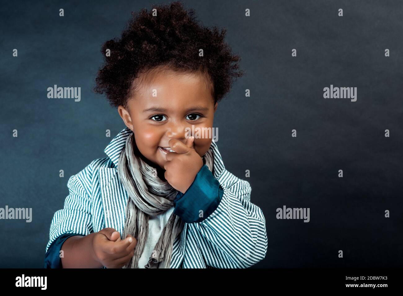 Portrait eines netten kleinen afroamerikanischen Jungen in stylischen Kleidern, der auf dunklem Hintergrund im Studio posiert. Babymodell. Stockfoto