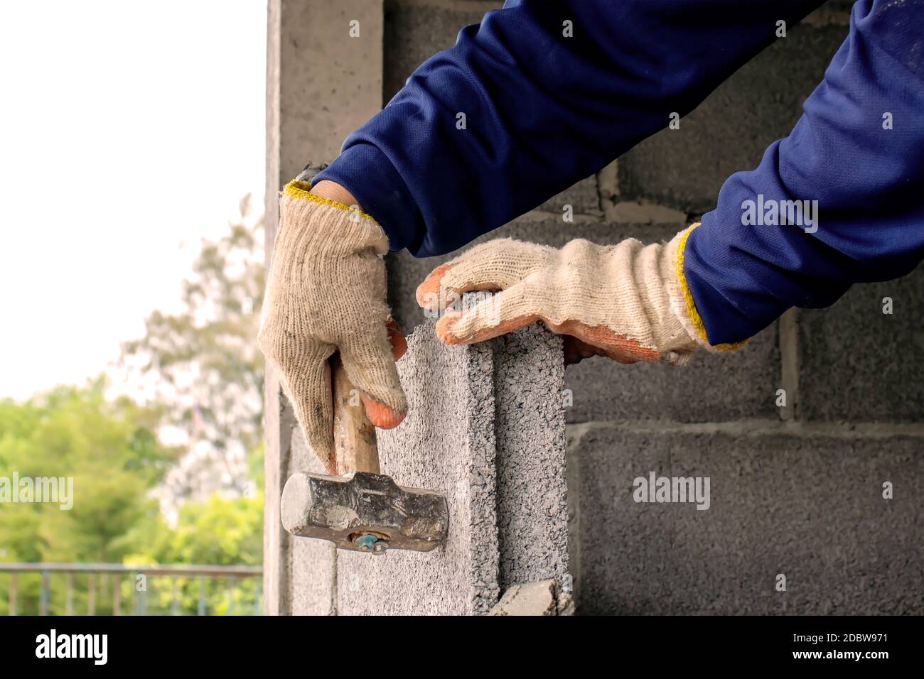 Bauarbeiter verwenden den Hammer, um die Ziegel auf die Ebene zu schlagen, um Zementwände, Hausbau und Innendekoration Ideen zu bauen. Stockfoto