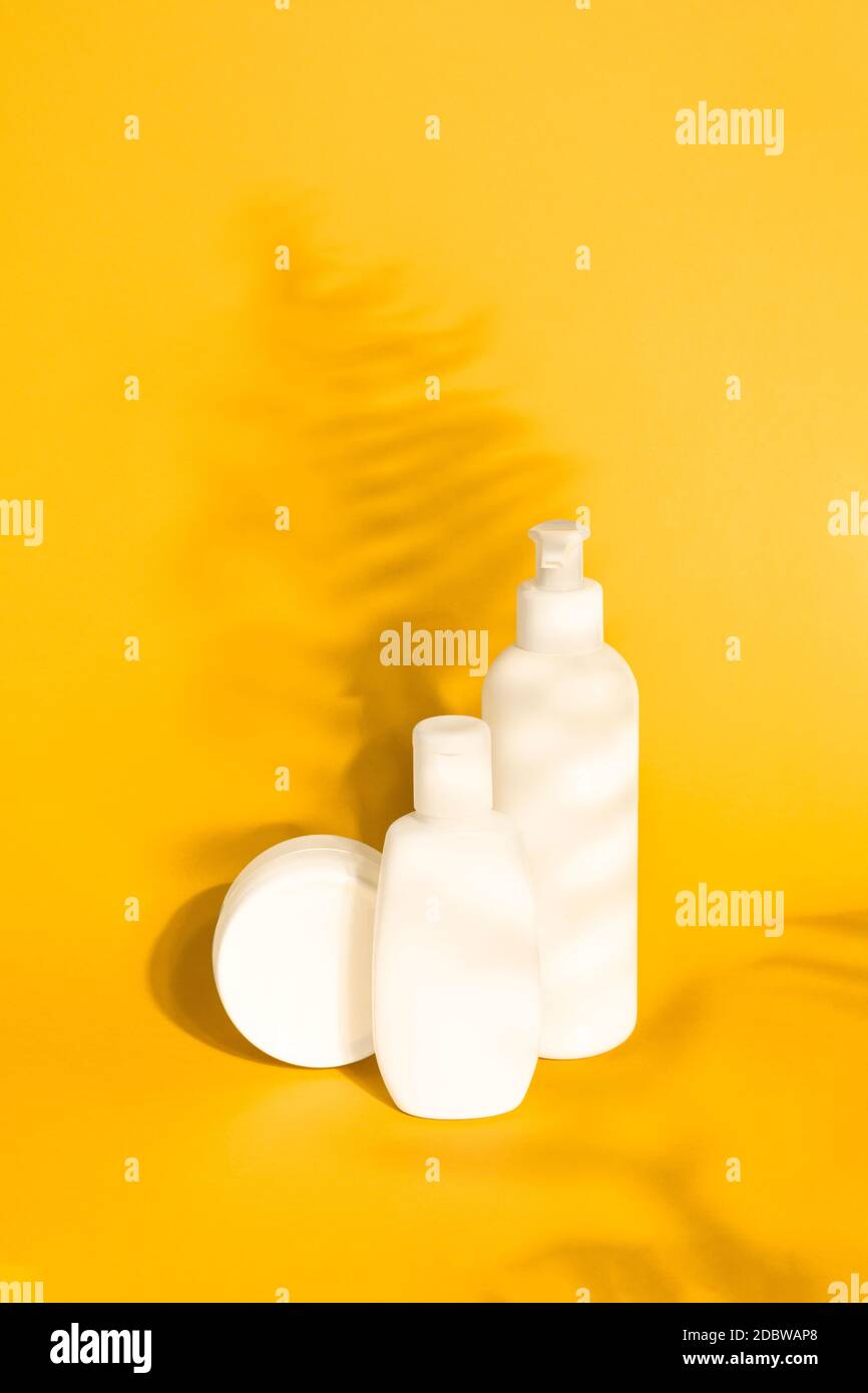 Set von Öko-Kosmetik-Produkte Mock up mit Schatten Farnblätter auf gelbem Hintergrund. Spender Flasche, Rohr, Glas Sahne. Branding, Etiketten, Verpackungen Stockfoto