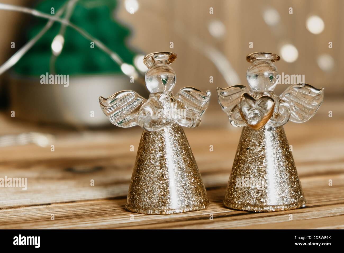 Weihnachtskarte mit zwei Engeln, Tannenbaum und Girlande auf Holzhintergrund. Defokussierten Lichter Hintergrund und Weihnachtsdekorationen. Selektiver Fokus. Stockfoto