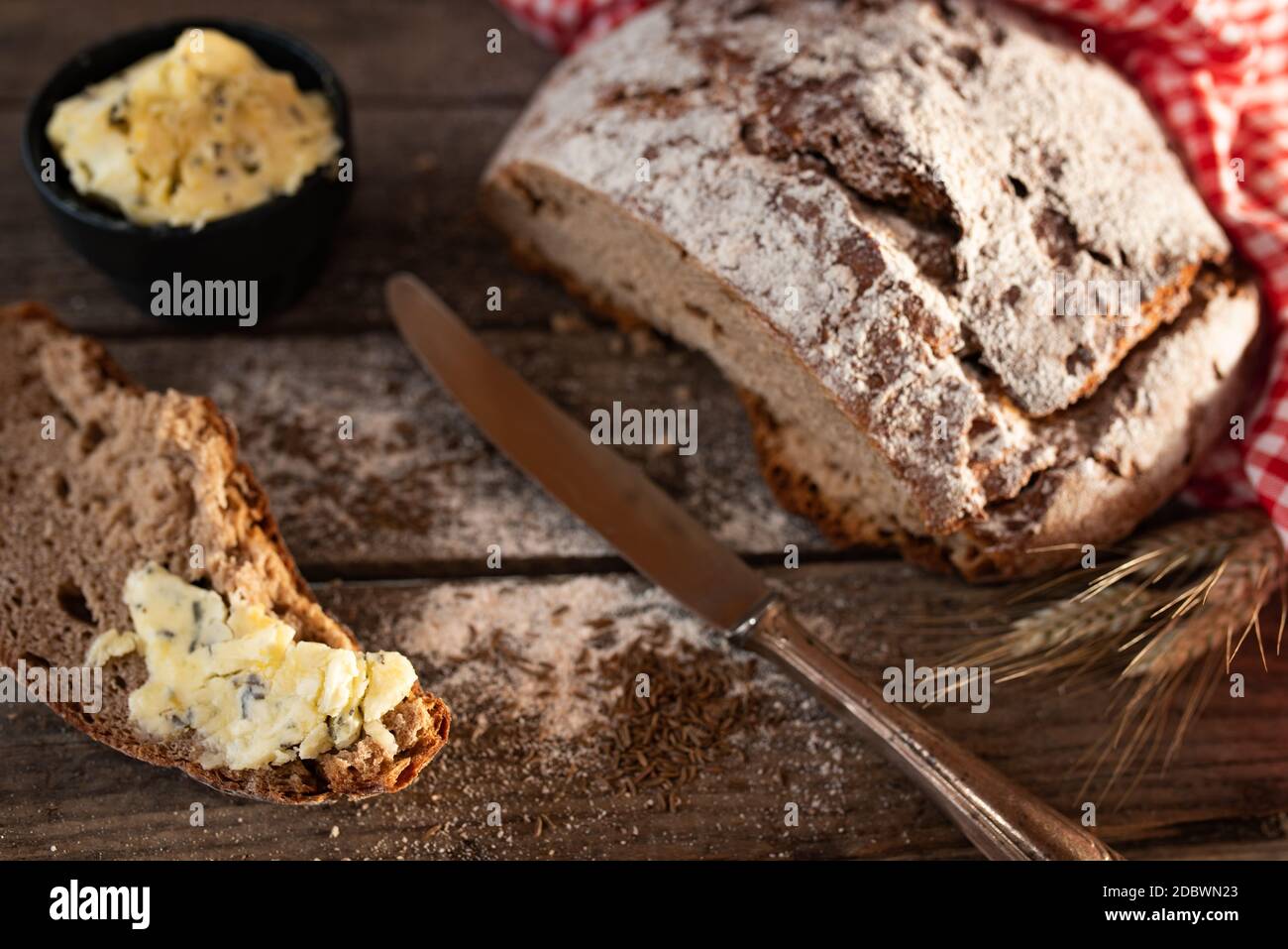 Frisch geschnittenes knuspriges Brot mit Kräuterbutter und Kuminon auf ...