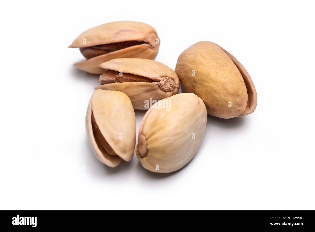 Fünf geröstete Pistazien in der Schale (Pistacia vera) auf weißem Hintergrund Stockfoto