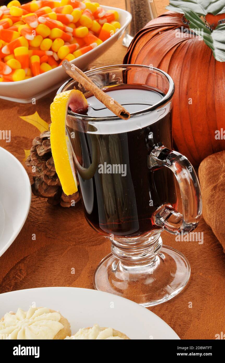 Ein Becher mit heißem Gewürzwein mit Zitronenverdrehung Und Zuckermais auf einem Halloween- oder Thanksgiving-Tisch Stockfoto