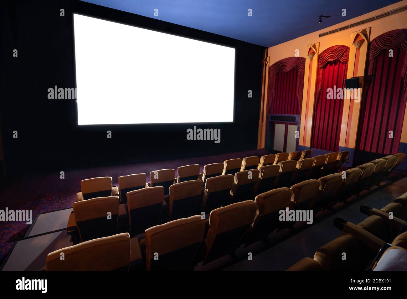 Kinoleinwand vor den Sitzreihen im Kino, auf der die weiße Leinwand vom Kinematographen projiziert wird. Das Kino ist eingerichtet Stockfoto