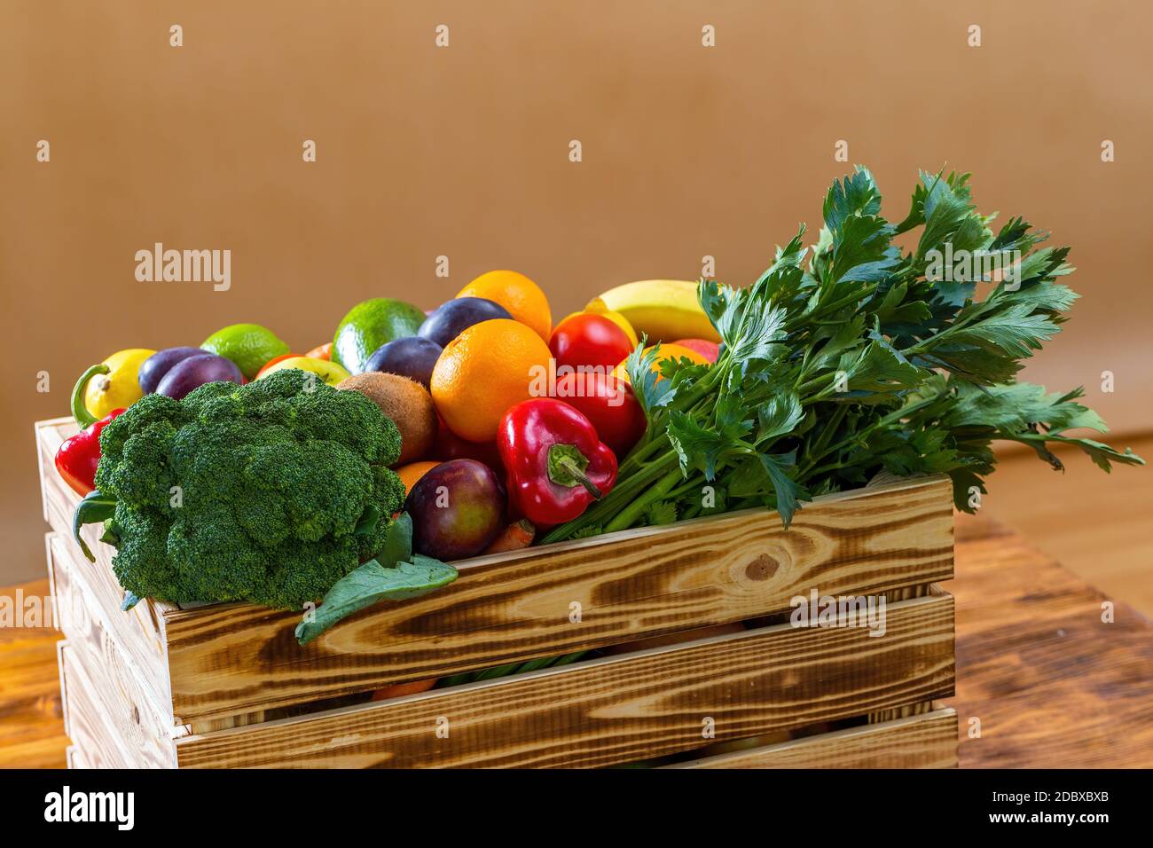 Holzkiste mit frischem Obst und Gemüse auf braunem Tisch. Stockfoto