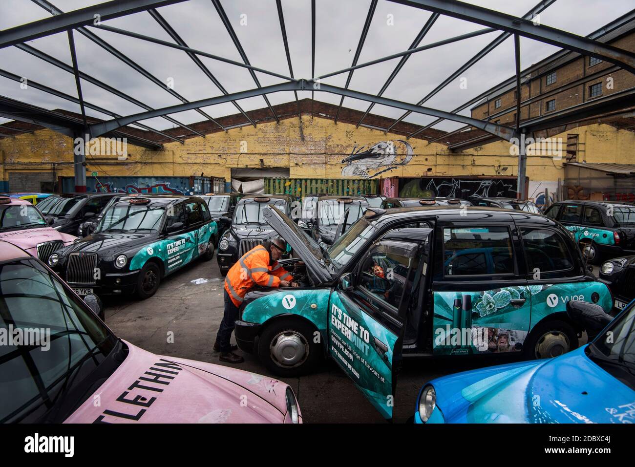 Ein Ingenieur arbeitet an einem entstellten schwarzen Taxi in einem Hof bei Sherbet London im Osten Londons, wo sich aufgrund eines starken Nachfragerückgangs eine große Anzahl von Londoner Miettaxis anbaut, da die Beschränkungen des Coronavirus die Reise- und Büroarbeit weiter reduzieren. Stockfoto
