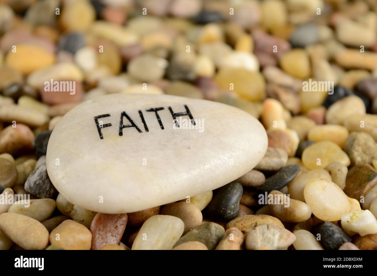 Ein glatter Flussstein ist mit dem Wort Glaube für spirituelle Affirmation Zwecke geätzt. Stockfoto