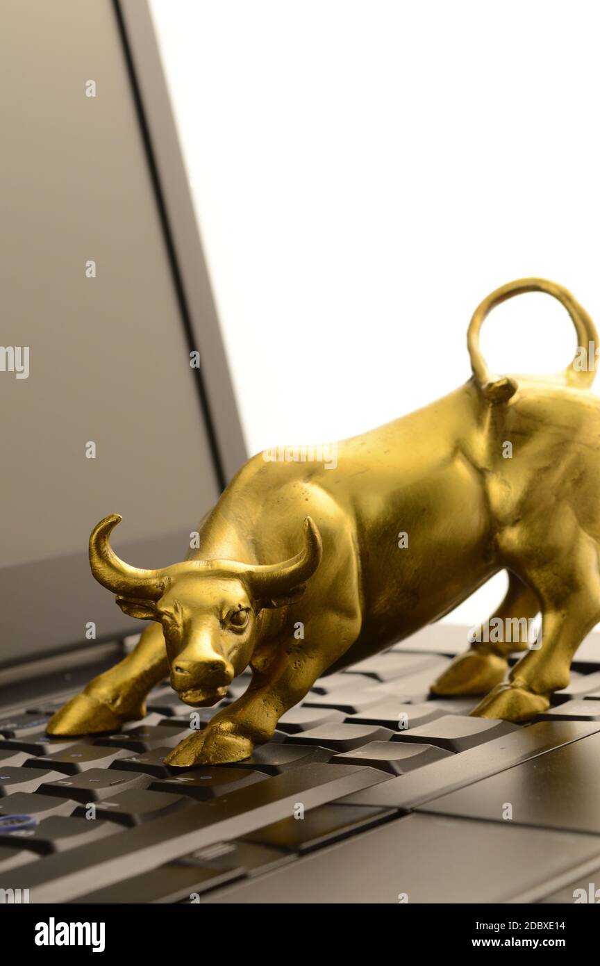 Ein Brass Bull und Laptop für Konzepte im Zusammenhang mit den Aufwärtstrends des Marktes. Stockfoto