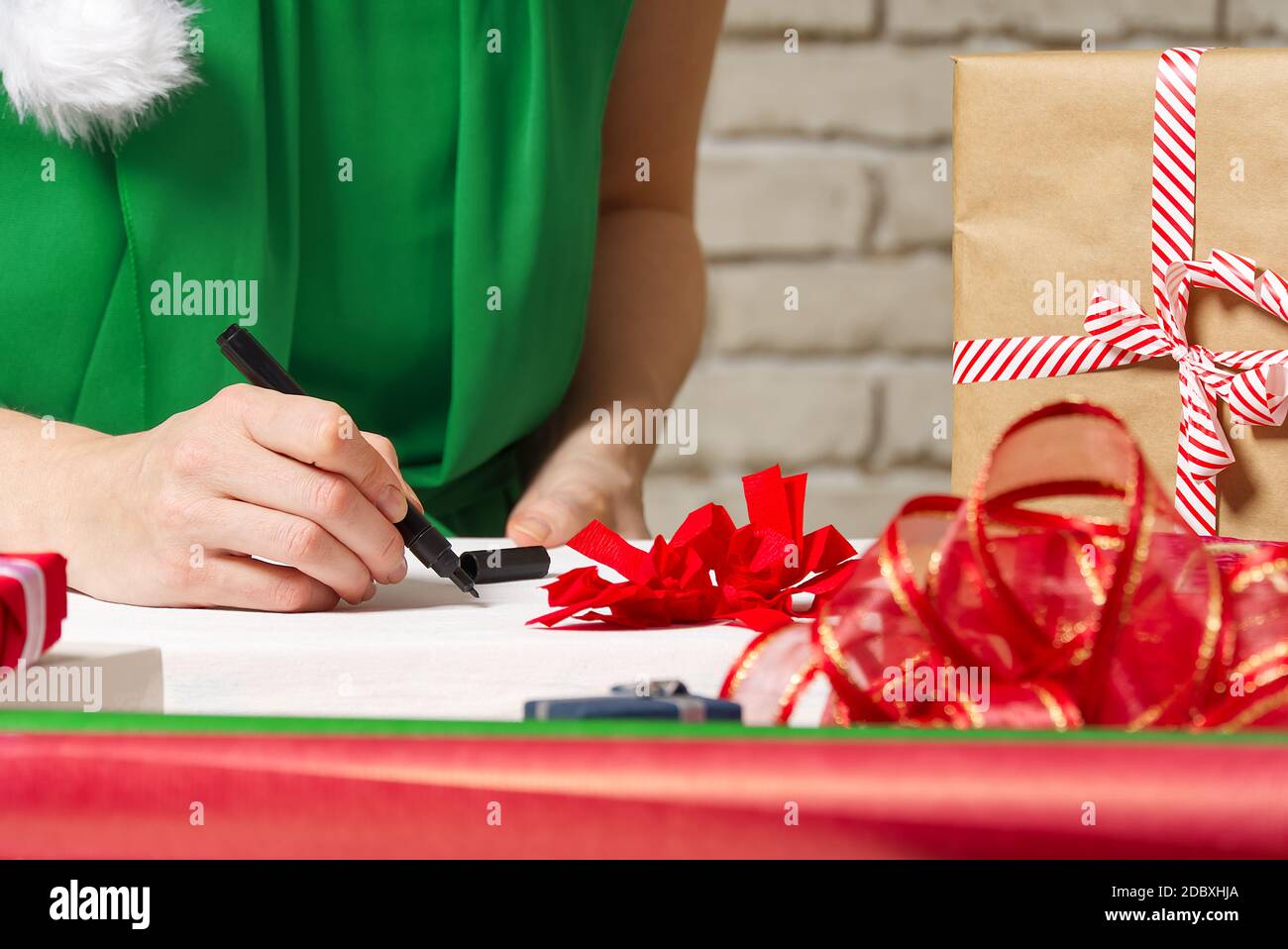 Frau unterzeichnet weihnachtsgeschenke mit einem schwarzen Stift. weihnachtsgeschenke Verpackung Stockfoto