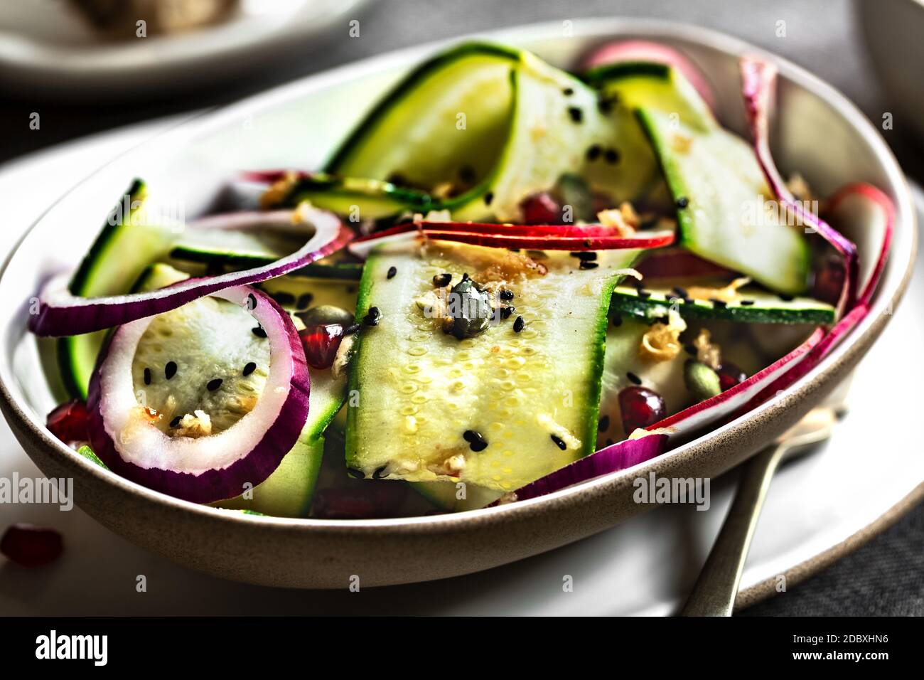 Zucchini, rote Zwiebel und Granatapfel mit Sesamsoja und Ingwer-Dressing Stockfoto