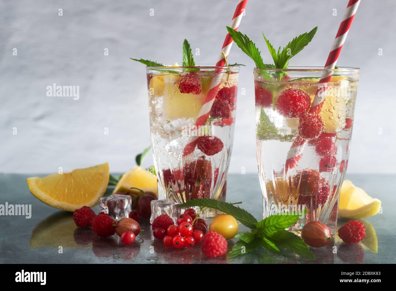 Erfrischender Cocktail aus natürlichen Früchten und verschiedenen Beeren mit Eis und Minzblättern, die mit Wasser durchtrinst sind. Enthält Zitrone, Himbeere, Kirsche, Gans Stockfoto