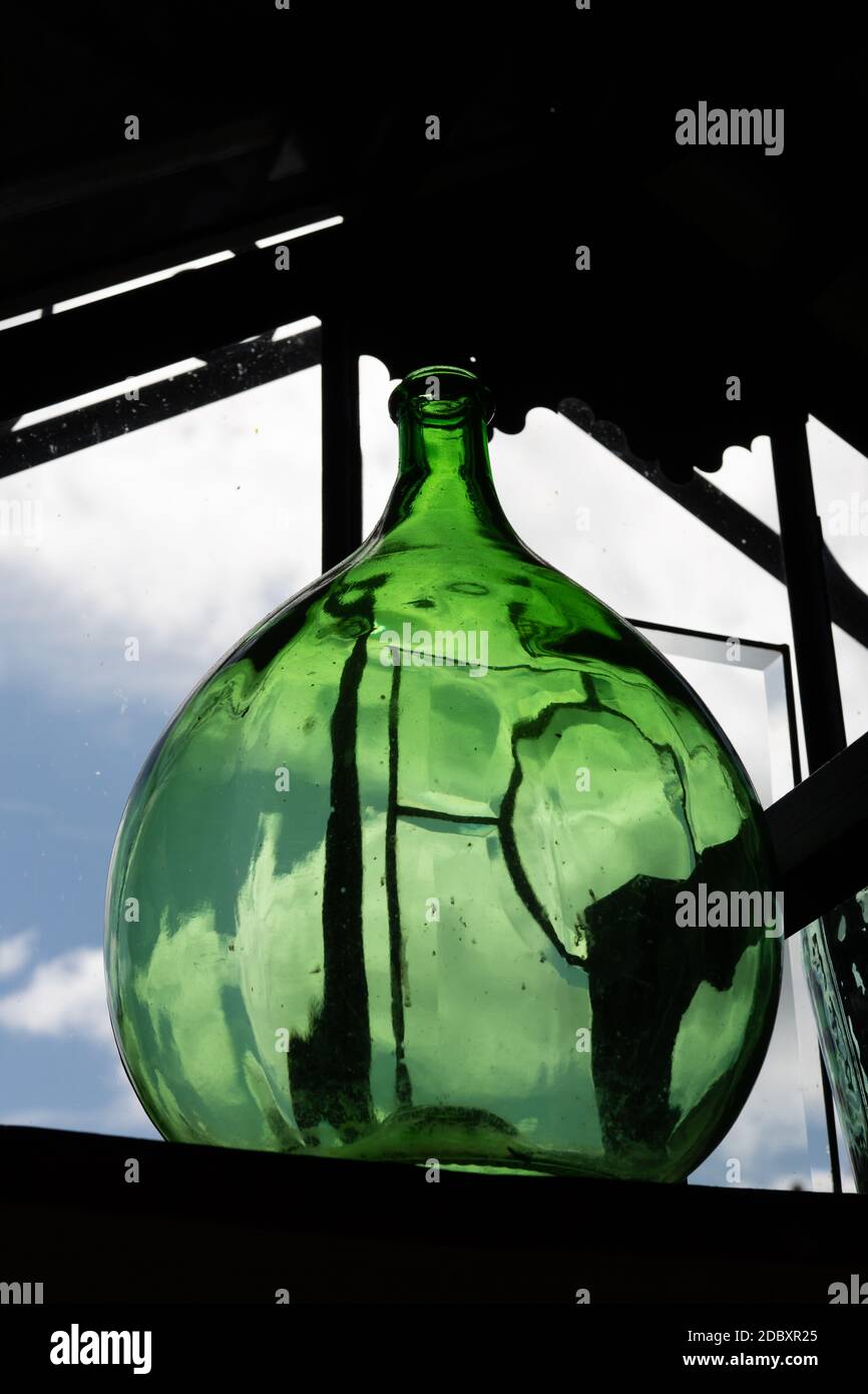 Grüne Flasche Dame Jeanne. Dekoratives Objekt auf der Veranda. Hochwertige Fotos Stockfoto
