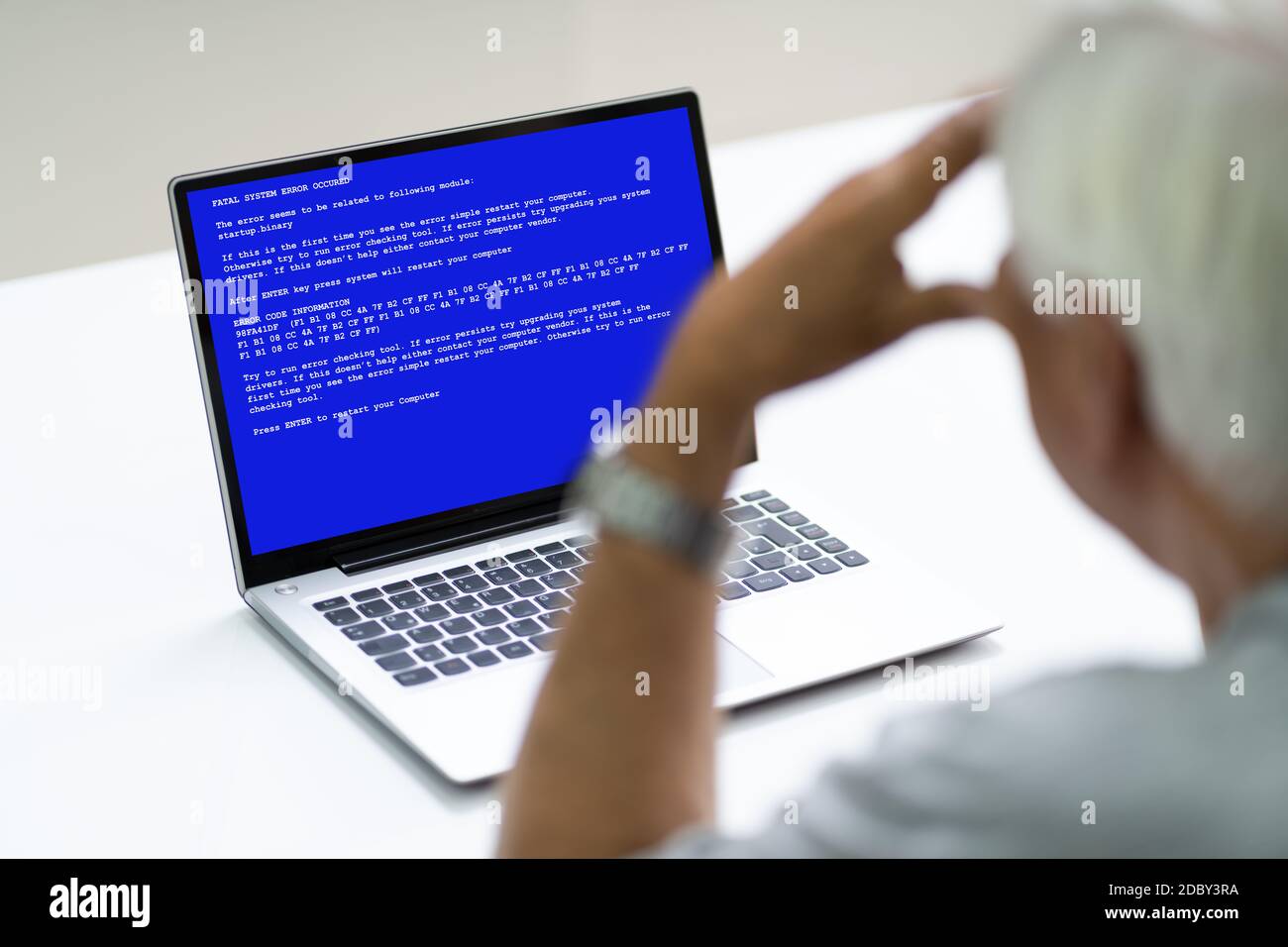 Senior mit BSOD Death Screen auf einem gehackten Laptop Stockfoto