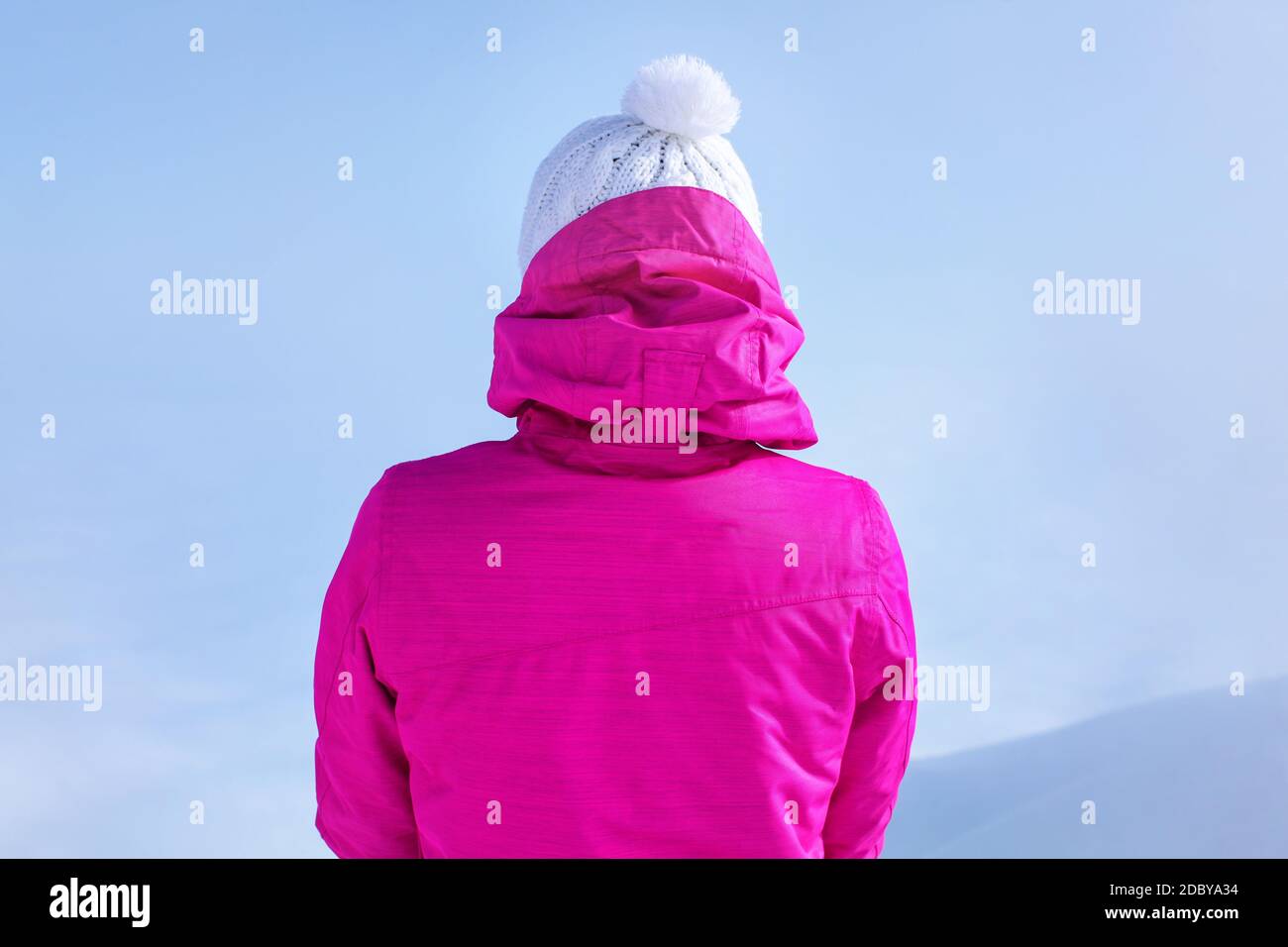 Detailansicht zurück zu von der jungen Frau in rosa Winterjacke stehen auf dem Gipfel des Berges. Stockfoto