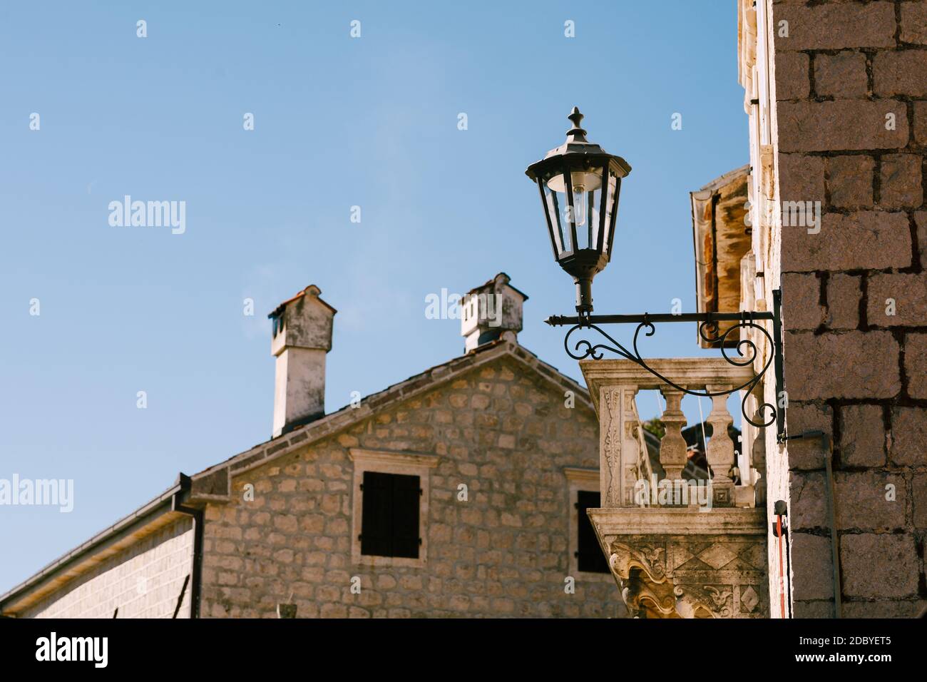 Straßenlampe an der Wand des Gebäudes in der Nähe des Balkons gegen den blauen Himmel. Stockfoto