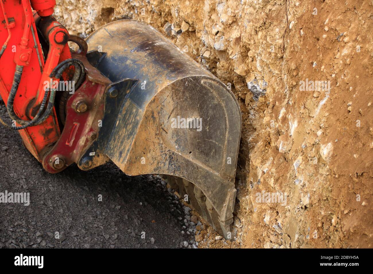 Bagger Schaufel gräbt in einen geschotterten Boden Stockfoto
