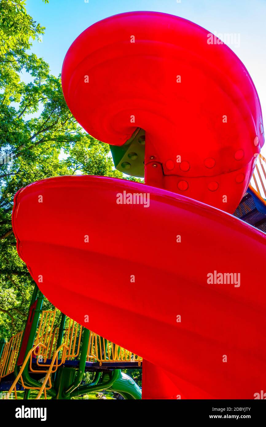 Leuchtend rote verdrehte Kinderspielplatzrutsche im öffentlichen Park Stockfoto