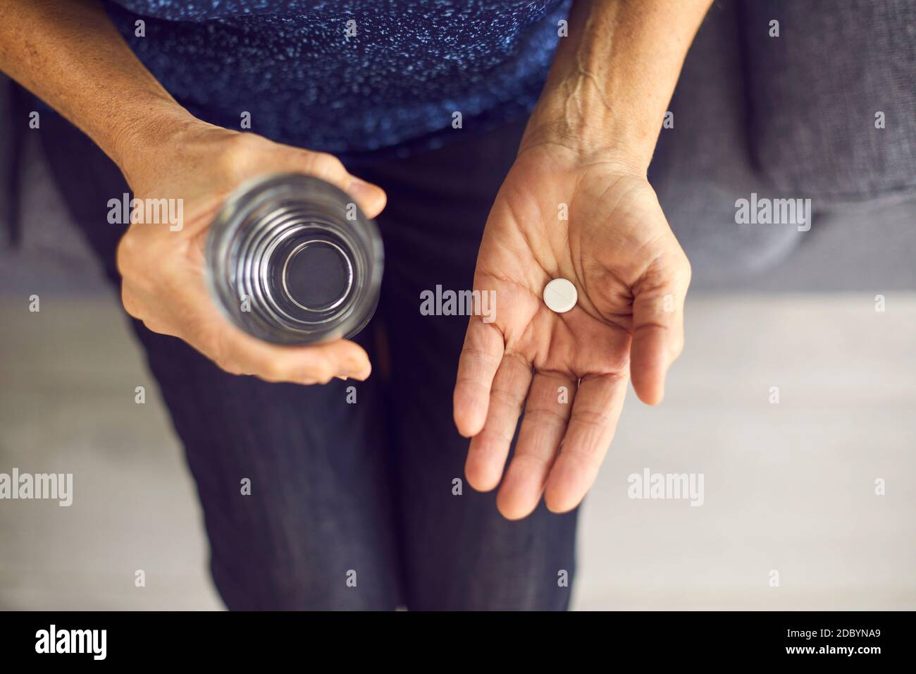 Zugeschnittenes Bild Nahaufnahme einer löslichen weißen Pille und einem Glas Wasser in menschlichen Händen. Stockfoto