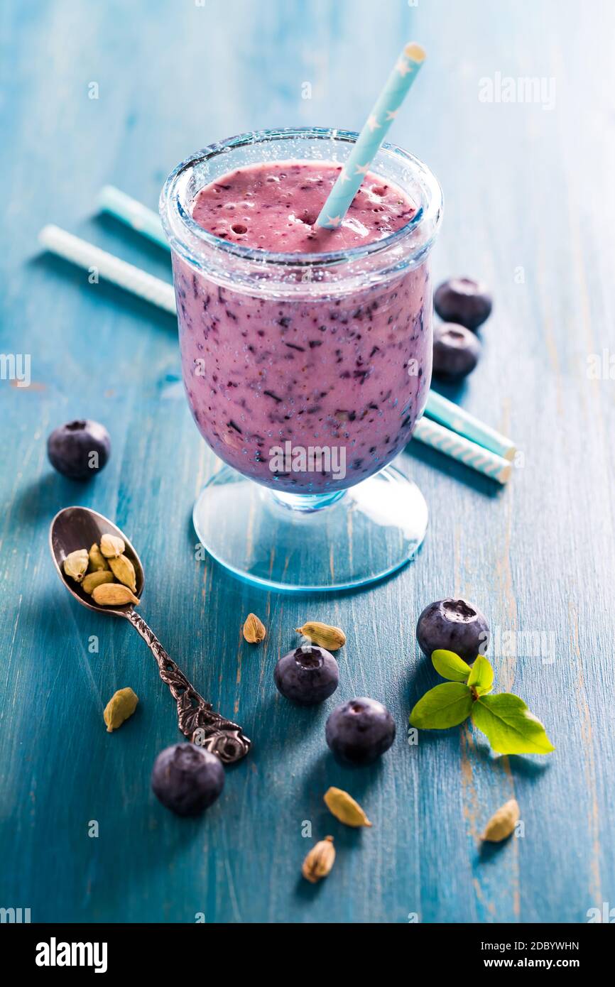 Gesunde Heidelbeere Lassi oder Smoothie trinken mit Kardamom auf blau Holzhintergrund Stockfoto