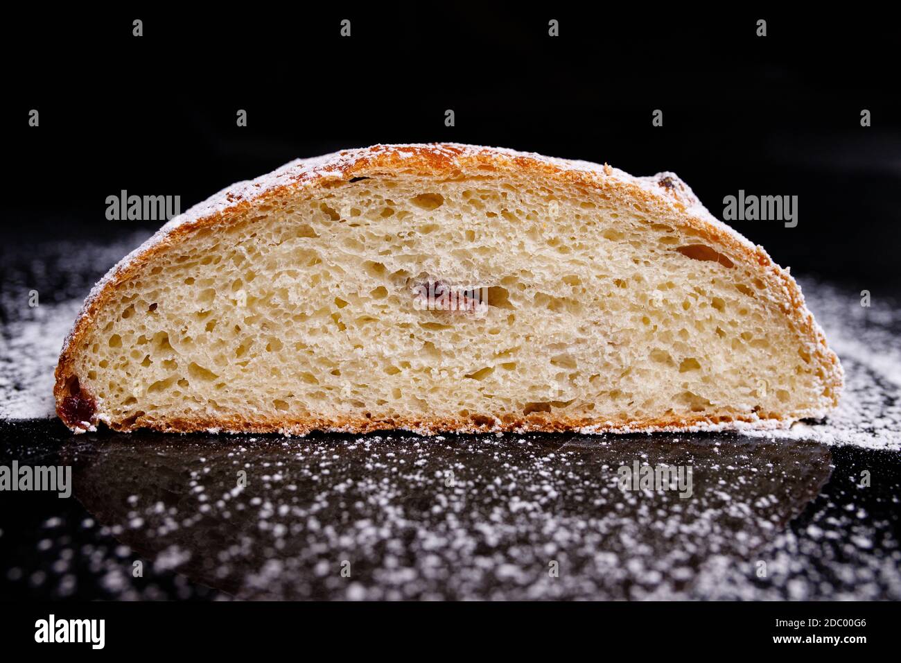 Süßer Cupcake in runder Brotform mit Füllung. Brot - Cupcake auf schwarzem Hintergrund, mit Pulver bestreut, mit Johannisbeeren verziert. Foto in secti Stockfoto