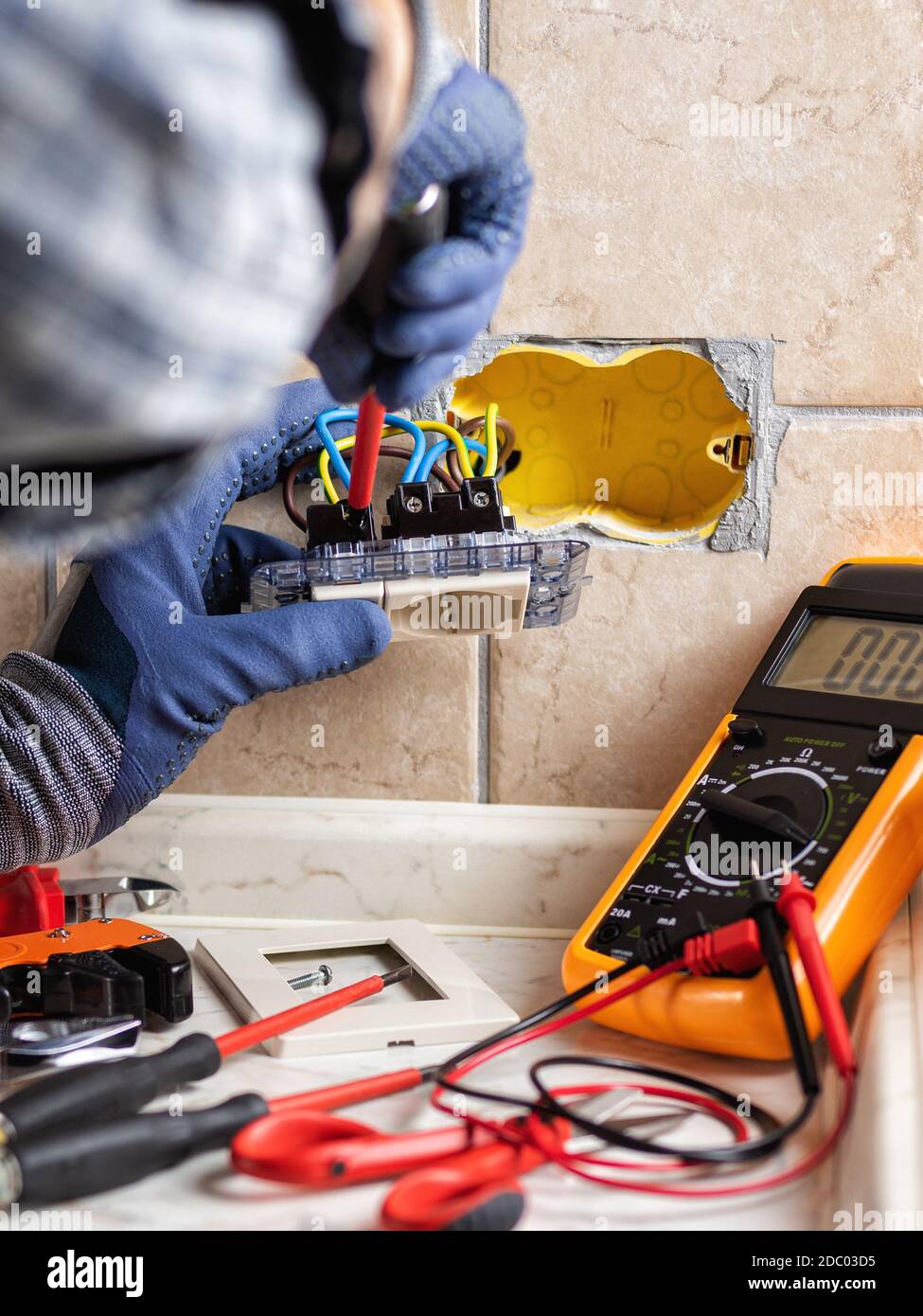 Elektriker bei der Arbeit mit Schraubendreher fixiert das Kabel in den Buchsen eines Wohnelektrik-Systems. Bauindustrie. Stockfoto