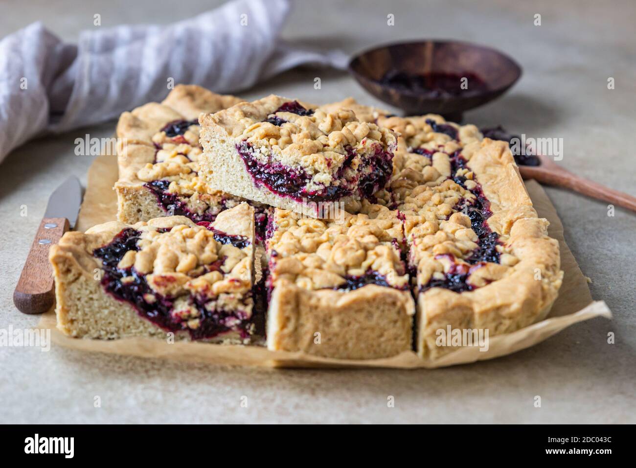 Hausgemachte Mürbeteig Beeren Marmelade Kuchen auf Backpapier, heller Hintergrund. Zerbröseln Sie den Kuchen. Stockfoto