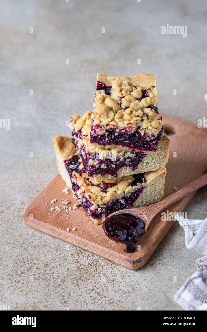 Mürbeteig Pie Bars mit Beeren Marmelade und bröckeln auf Holzbrett, heller Hintergrund. Hausgemachte Bäckerei. Stockfoto