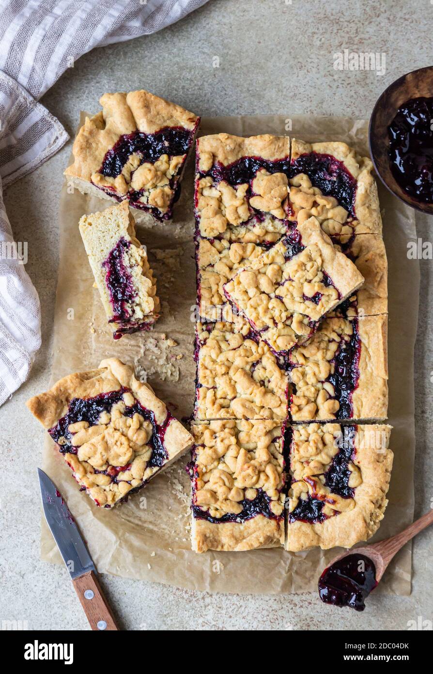 Hausgemachter Mürbeton Beeren Marmelade Kuchen auf Backpapier, heller Beton Hintergrund. Zerbröseln Sie den Kuchen. Draufsicht. Stockfoto