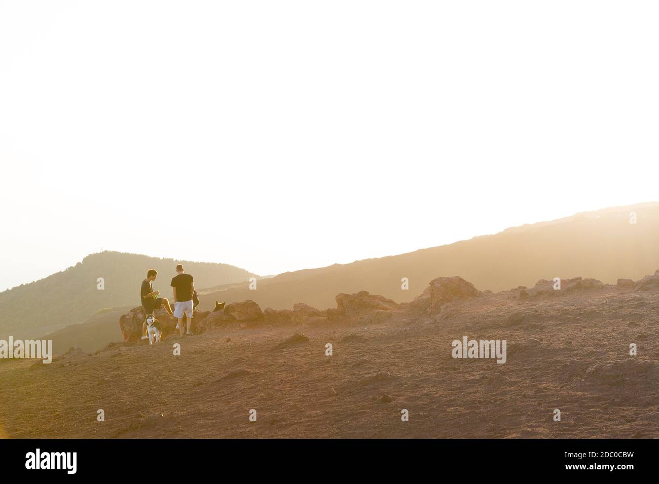 Sizilien, Italien. Zwei Einheimische sitzen mit ihren Hunden am Silvestri Inferiore Krater nahe dem Gipfel des Ätna. Stockfoto