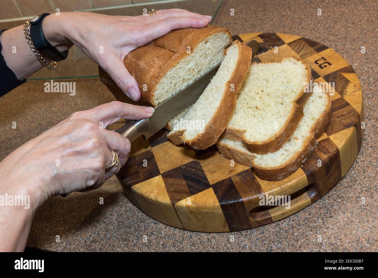 Hände schneiden einen weißen Laib Brot. Selbst gebacken. Stockfoto