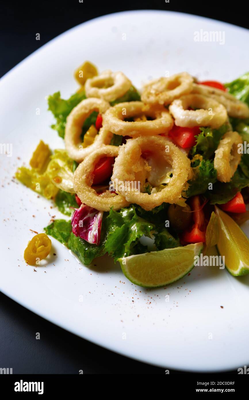Tintenfisch-Salat serviert mit frischem Gemüse, Limettenzitronen.köstliche mediterrane Speisen zubereitet Mit traditionellen italienischen Rezept im Fischrestaurant.Calamari Stockfoto