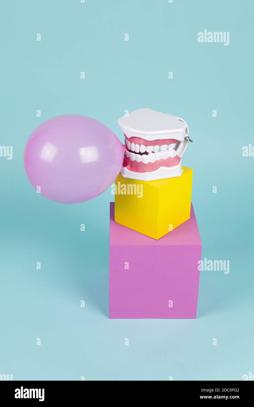 Ein anatomisches Zahnmodell aus Kunststoff, um zu lernen, wie man Zähne putzt, indem man einen Kaugummiball auf farbigen Würfeln hält. Unkonventionaler Humor und Pop-Atmosphäre. Minimal Stockfoto