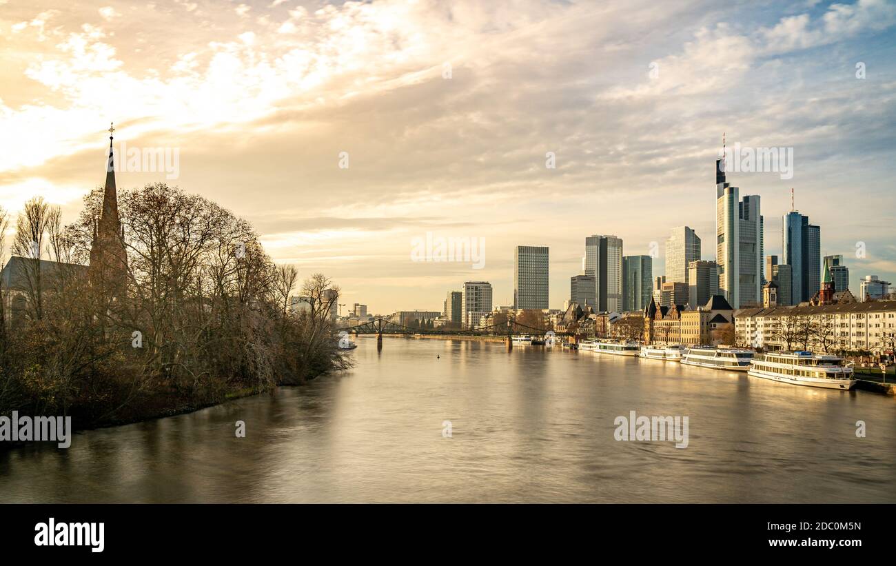 Frankfurter Skyline und Kirche, die bei Sonnenuntergang mit Reflexionen im Main, Frankfurt am Main, Deutschland Stockfoto