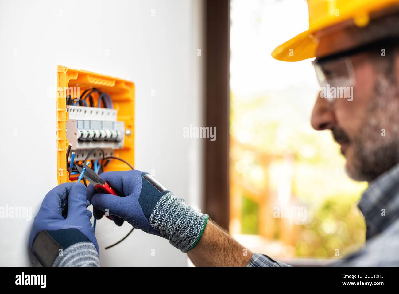 Elektriker bei der Arbeit bereitet elektrische Kabel in der Schalttafel einer elektrischen Wohnanlage vor. Bauindustrie. Stockfoto