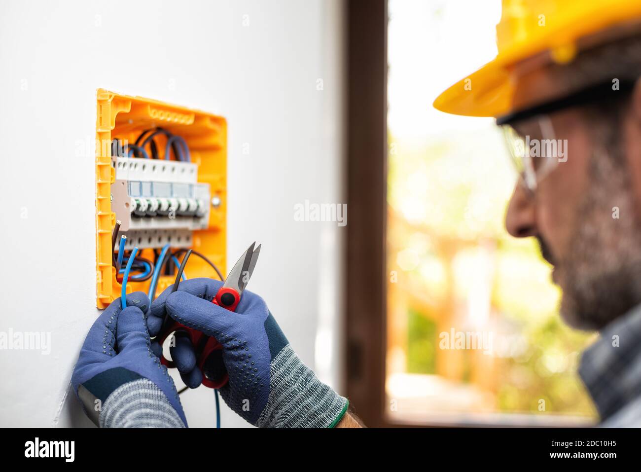 Elektriker bei der Arbeit bereitet elektrische Kabel in der Schalttafel einer elektrischen Wohnanlage vor. Bauindustrie. Stockfoto