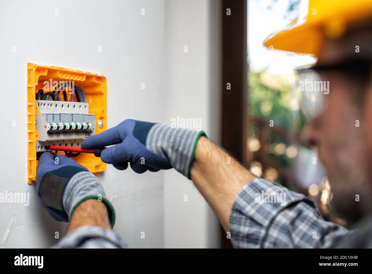 Elektriker bei der Arbeit mit Schraubendreher fixiert das Kabel in den Schaltern einer elektrischen Zentrale in einer Wohnanlage. Bauindustrie. Stockfoto