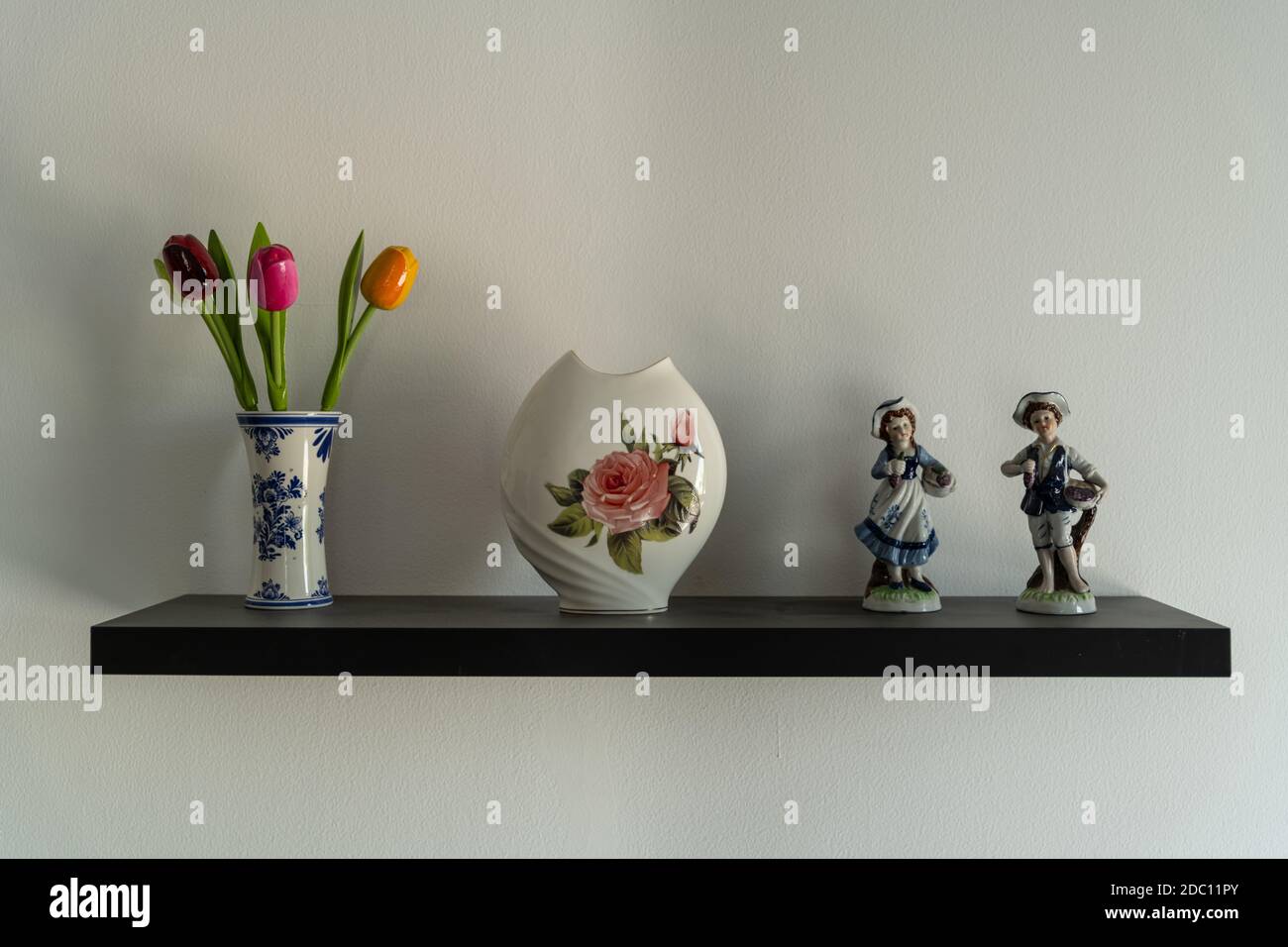 Ein flaches Stück braunes Holzregal, an der Wand befestigt und ein paar Ausstellungsstücke darauf platziert. Stockfoto