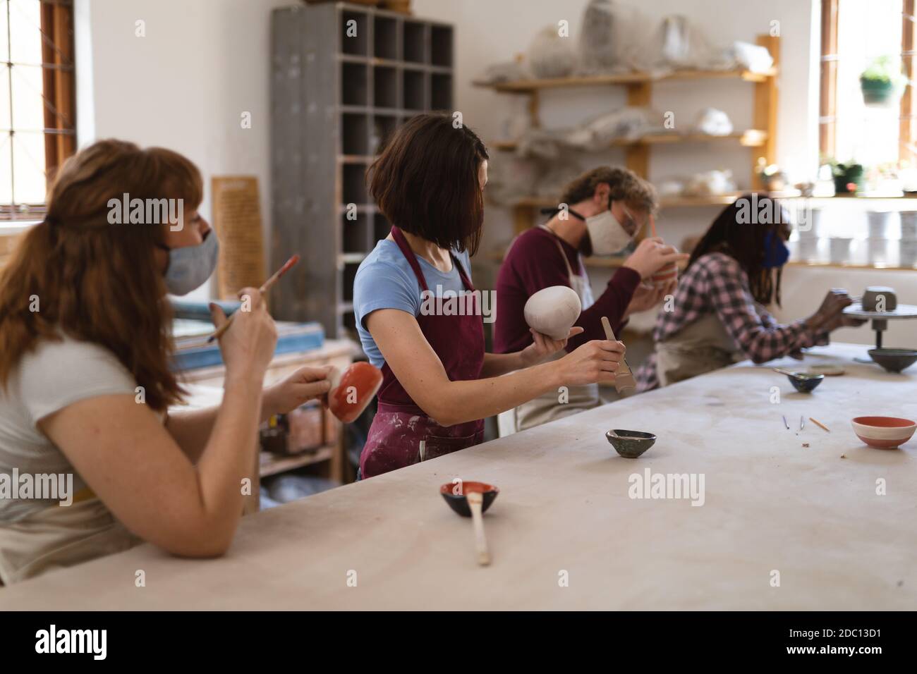 Multi-ethnische Gruppe von Töpfern in Gesichtsmasken arbeiten in Keramik studio Stockfoto