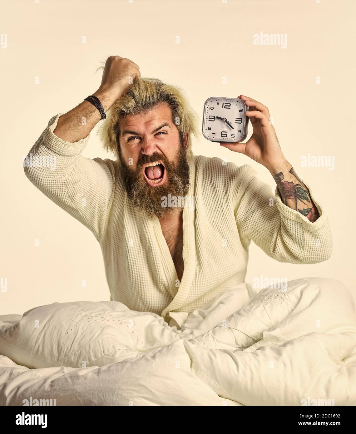 Selbstdisziplin. Erschöpfter Mann, der durch Wecker im Schlafzimmer geweckt wurde. Reifer Mann auf Bett Ausschalten Uhr. Reifer Mann ausschalten Wecker. Digitaler Wecker im Schlafzimmer. Zeit zum Aufwachen. Stockfoto