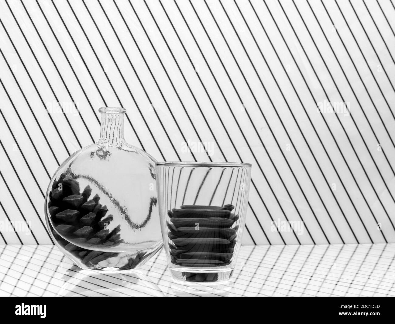 Schwarz-weiß monochrom Wasser Verzerrung, Reflexion, Brechung durch Glas und Flasche. Mit Tannenzapfen. Stockfoto