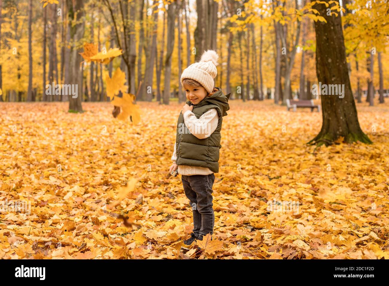 Kleiner Vorschuljunge im Herbstpark mit goldenem Laub übersät. Das Konzept der Spaziergänge im Freien, Spaß mit Kindern. Foto in voller Länge Stockfoto