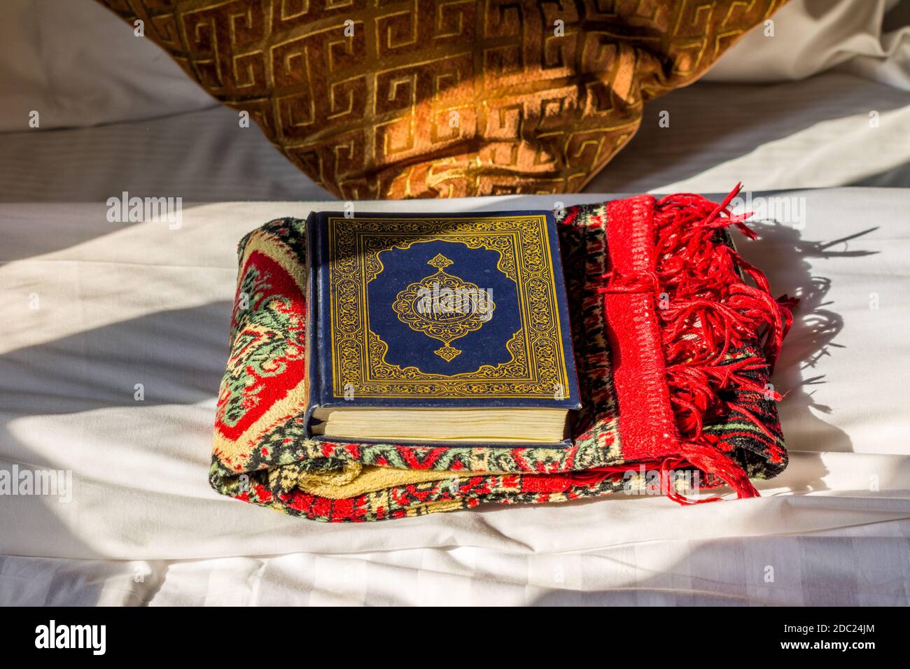 Koran bibel und ein Schal auf dem Bett mit Hintergrund Von Kissen unter Sonnenlicht im Hotel von Saudi-Arabien Stockfoto
